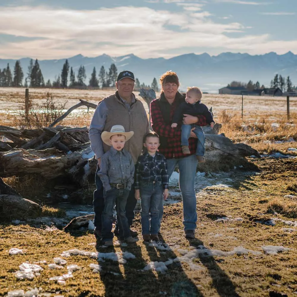 Bob and Laurie Sutherlin standing with their grandchildren in a winter pasture