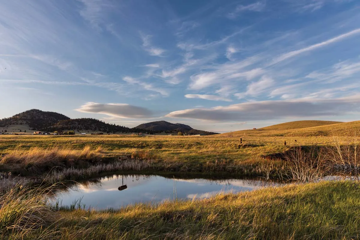 Open grassland and ponds near Fort Harrison with low hills on the horizon
